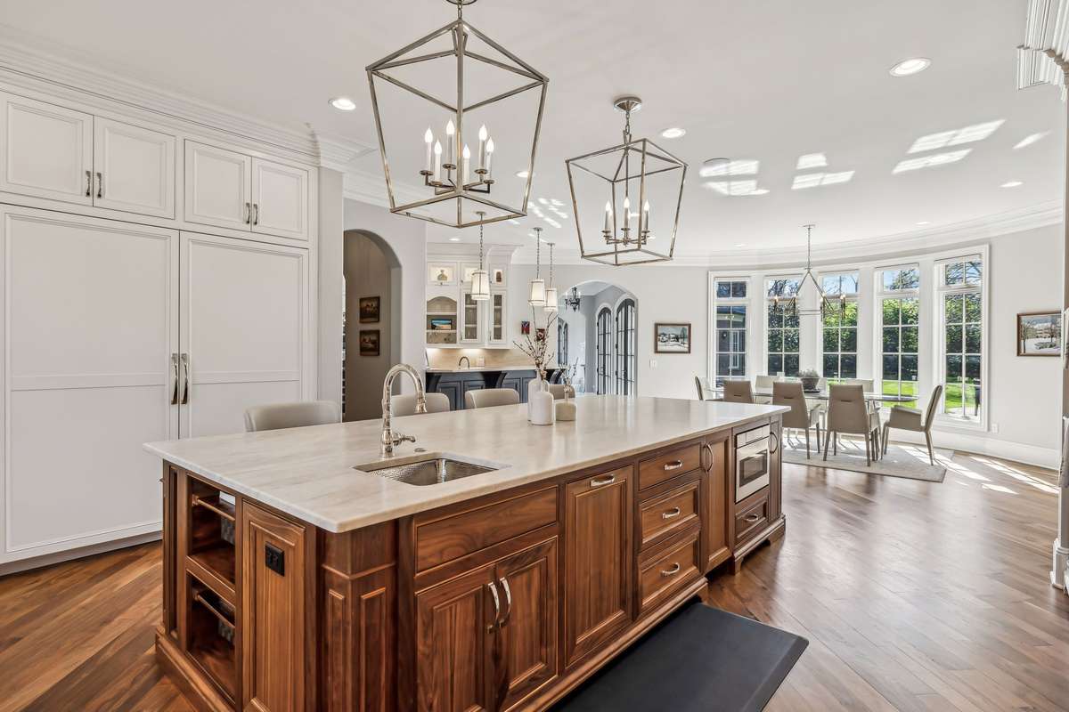 The expansive island invites gathering, with features like a built-in microwave, hammered stainless steel prep sink, trash and recycling pullouts, cookbook storage, and even potato/onion bins and a discreet toe-kick vacuum outlet.