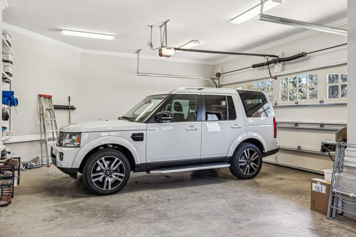 Key features include insulated garage doors for enhanced temperature control, a convenient pedestrian door for easy access, and custom-built storage shelves designed for durability.