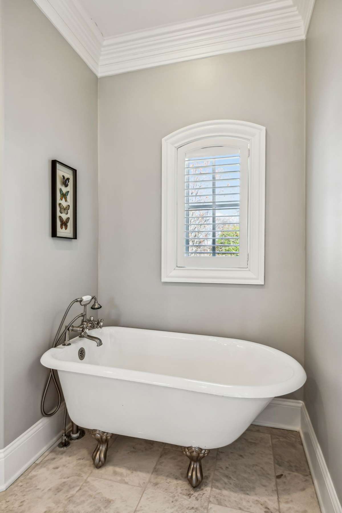 Elegant marble tile flooring sets the tone, complemented by a timeless clawfoot tub and a sophisticated vanity topped with a marble countertop, complete with drawer stack and ample cabinet storage.