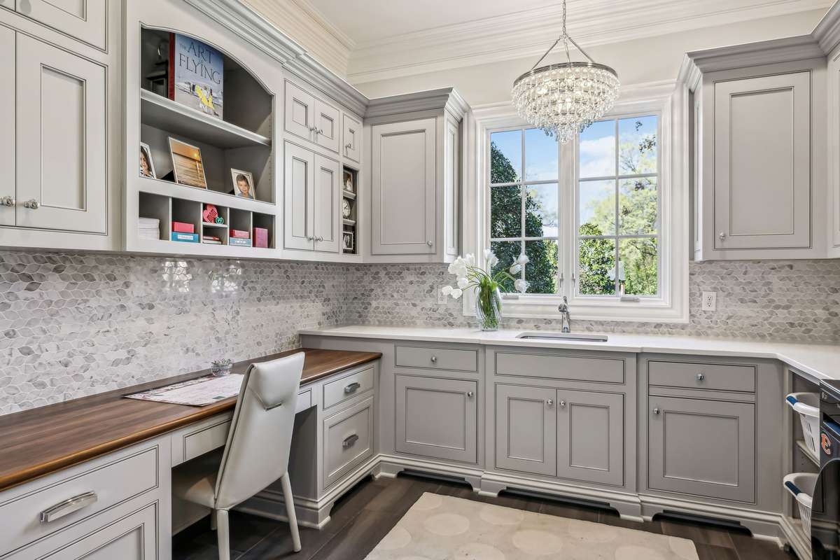 This expansive Laundry Room transforms everyday tasks into an enjoyable experience. Custom cabinetry topped with quartz counters provides ample workspace and storage, while a built-in desk area with a walnut surface adds warmth to the space.