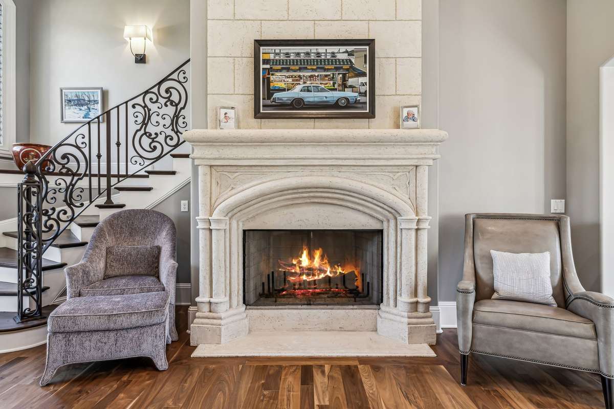 The curved staircase is a true work of art—adorned with rich hardwood treads, intricate iron spindles, and a striking leaded glass window that casts a soft, luminous glow.