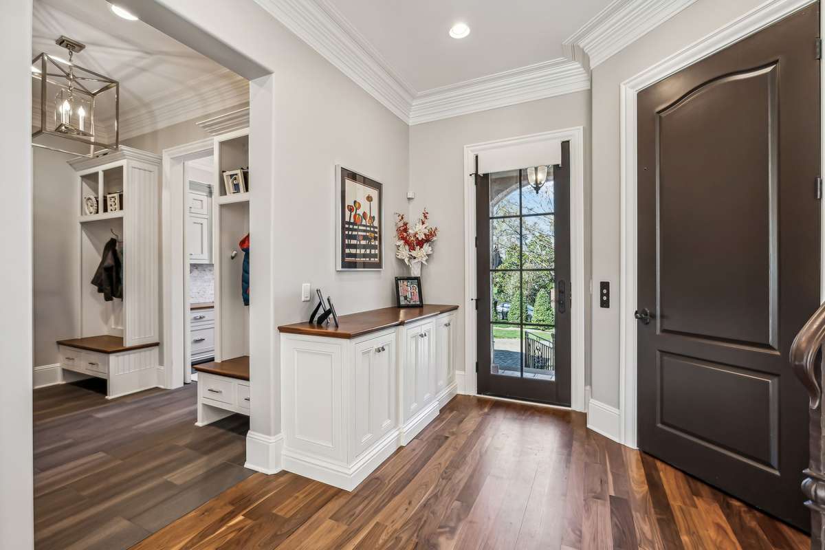 Just steps away, the covered Friend’s Entry features a counter-height built-in cabinet—ideal for stashing keys, purses, or mail—and offers easy access to both the back staircase and the elevator, enhancing flow and everyday convenience.