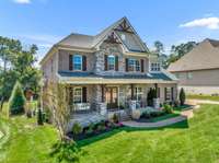 A grand covered front porch with stained cedar beams is a great place to enjoy those Spring mornings and provides shelter for guests from the elements as they enter the home.