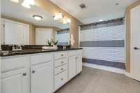 Primary Bathroom with double vanities, granite countertops, tile flooring, and separate water closet.