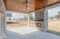 Stunning covered back patio features wood ceiling and fireplace