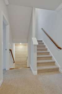 Staircase view from 2nd floor landing to 3rd level.  Wood shiplap accent in landing area.