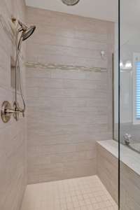 Walk-in shower with seated bench and seamless shower door/surround.