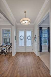 View of entry from the living areas shows the beautiful millwork.  Front door glass filters allow for light while maintaining privacy.  Hardwoods throughout the first floor except the guest suite.