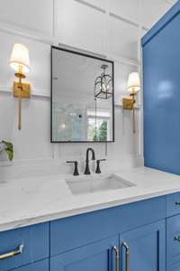 One of the vanities has a recessed medicine cabinet. Both vanities have sconces. Notice the wood accent details on the walls.