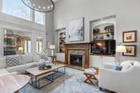 Living area has gas fireplace with custom wood mantel.  Custom built-ins have same wood accents with cabinet storage below and wood shelves above. New light fixture brightens the space. Surround sound is throughout the house.