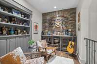 Bar/lounge area has built in bookcase w/lower  storage cabinets. Built-in dry bar has wire-front cabinet storage & unique concrete top. Stacked stone arch, rustic wood inset & accent lighting make this a special spot for relaxing & cozy chats.