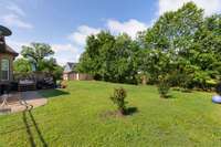 This view showcases the backyard's well-maintained charm, featuring a paved outside pathway that meanders through the lush green surroundings. 1001 Loblolly Dr.  Murfreesboro, TN 37128