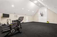 Enjoy a half-court gym upstairs.  The ceiling is 20 ft.  Currently, they have it housed with weight equipment in the back. There is a vinyl wood floor underneath the rubber matting.