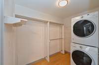 Large closet with wooden shelving and room for washer/dryer