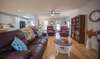 This living room is a perfect blend of comfort and style, inviting enjoyment for residents and guests alike with its stylish ceiling fan bringing refreshing air circulation and the warmth and brightness from the light-colored hardwoods.