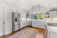 Custom cabinets, quartz countertops, stainless french door refrigerator, gas range, and large walk-in pantry