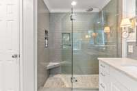 Custom walk-in tile shower with a full glass shower door. The toilet closet to the left