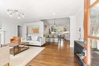 Step through the front door into the formal living room, one of three inviting living spaces, adorned with exquisite hardwood floors and a charming wood-burning fireplace