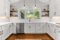 This inviting kitchen invites you with its charm. The floating wood shelves add a touch of warmth to the crisp and timeless style, making it a truly welcoming space