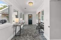 The herringbone tile in this breezeway adds a touch of character and warmth. Straight ahead, you'll find access to the attached two-car garage, studio/flex space, and the fourth ensuite bedroom