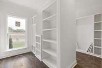 Double-sided closet in the Primary Suite. Custom wooden shelving with plenty of hanging and shelf space.