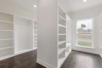 Double-sided closet in the Primary Suite. Custom wooden shelving with plenty of hanging and shelf space.