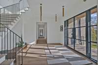 The view of the foyer, looking back out the front door and down the hall to your primary bedroom and office.