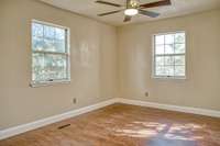 PRIMARY BEDROOM WITH NEW WOOD FLOORING, NEW CEILING FAN, FRESHLY PAINTED