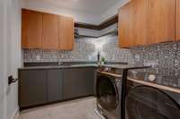 Spacious Laundry on second floor with sink and storage cabinetry.