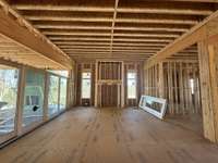 Oversized Great Room with Gas Fireplace - stone / pure white arcusstone, 13' ceiling,  10' Stained Beams, Slider doors open onto Covered Living Area   *this house is under construction  Built by: Legend Homes Photo taken 3/18/24