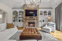 Built-in bookcases and a natural stone fireplace with a dramatic chandelier.