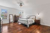 Spacious primary bedroom on main level with beautiful wood floors, shiplap and lots of light.