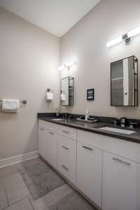 Primary bathroom features a double vanity with granite countertop and a walk in shower.