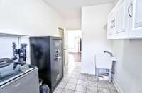 Convenient utility sink & storage options in this tiled laundry room.