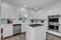 Beautiful Kitchen with double ovens, cooktop, and farmhouse sink under window overlooking the pool