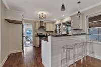 The kitchen has bright white cabinetry and white subway tile backsplash