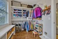 Primary walk-in closet with custom wood closet fixtures