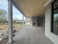 Rear Porch with wood burning fireplace looking over POOL AND SPA. *This home is under construction. Photo updated 12/19/23.