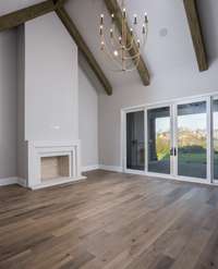 Grand great room boasts a vaulted ceiling with sliding glass doors, wood-burning fireplace and open-concept breakfast room.    This home is virtually staged. Built by: Schumacher Homes, LLC