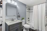 This full bathroom has a tile surround shower/tub combo.