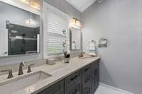 This primary full bathroom has dual vanities and plenty of cabinet storage.