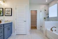 Primary suite features double vanities, tile flooring, and tile shower or tiled shower/garden tub.