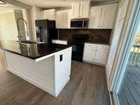 Large island with Sink and Dishwasher. Lots of cabinetry with Refrigerator, Stove and Microwave.