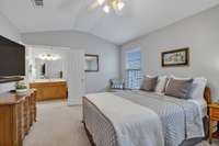 With a vaulted ceiling and double doors leading to the primary bath, the room has a grand feel