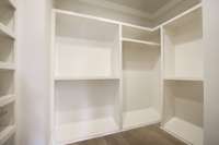 Large custom walk in closet with slanted shoe shelving on the bottom.