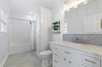 Updated bathroom has new tile, light fixture, paint, vanity and backsplash