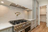 6-burner gas stove with built-in pot-filler.  Fridge is hidden behind custom-cabinet doors