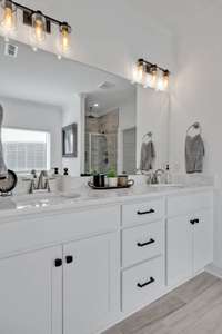 The master bath features double vanities with personal cabinets beneath each sink and a stack of drawers for additional storage. The cabinet hardware in this room has also been updated.