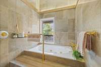 The walk-in tub and shower space features the original stone tile, a light rail, a towel warmer…