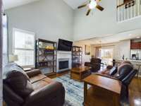 View from near the front door showing living space with two story ceiling, dining space, kitchen bar in open floor plan.